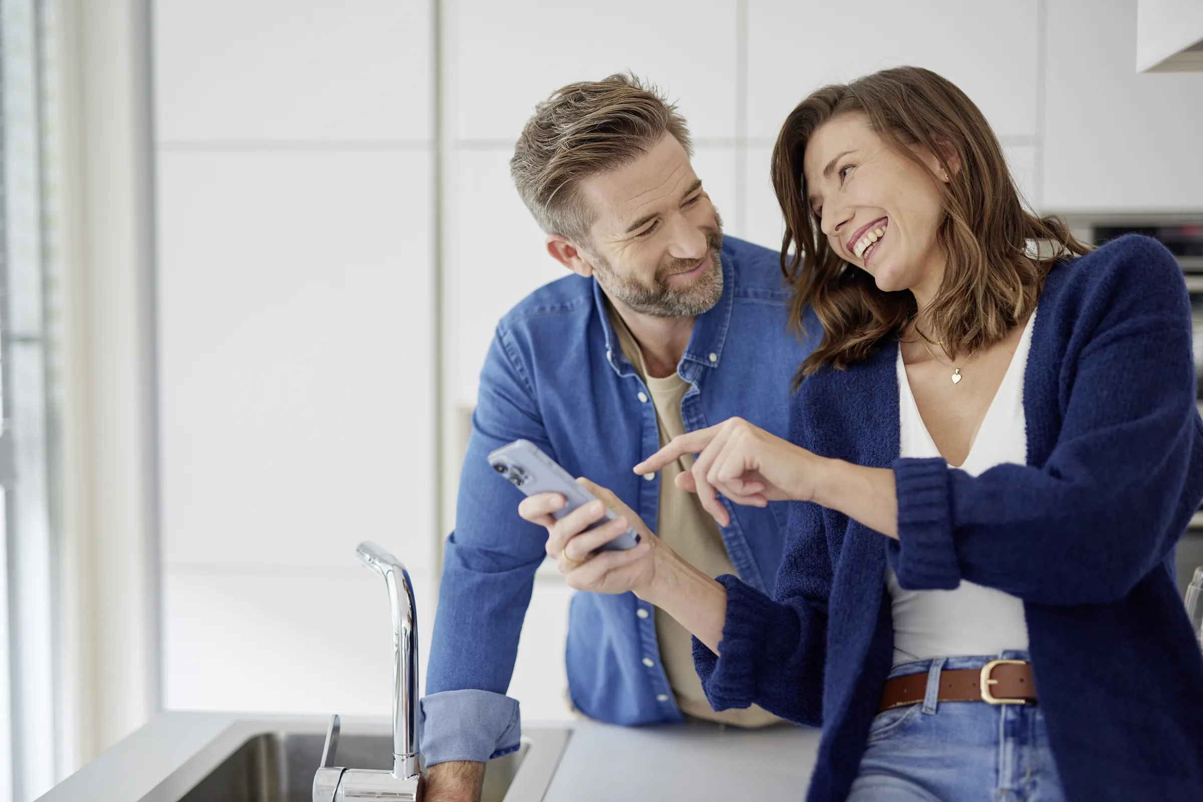 A couple in a kitchen looking at a phone together