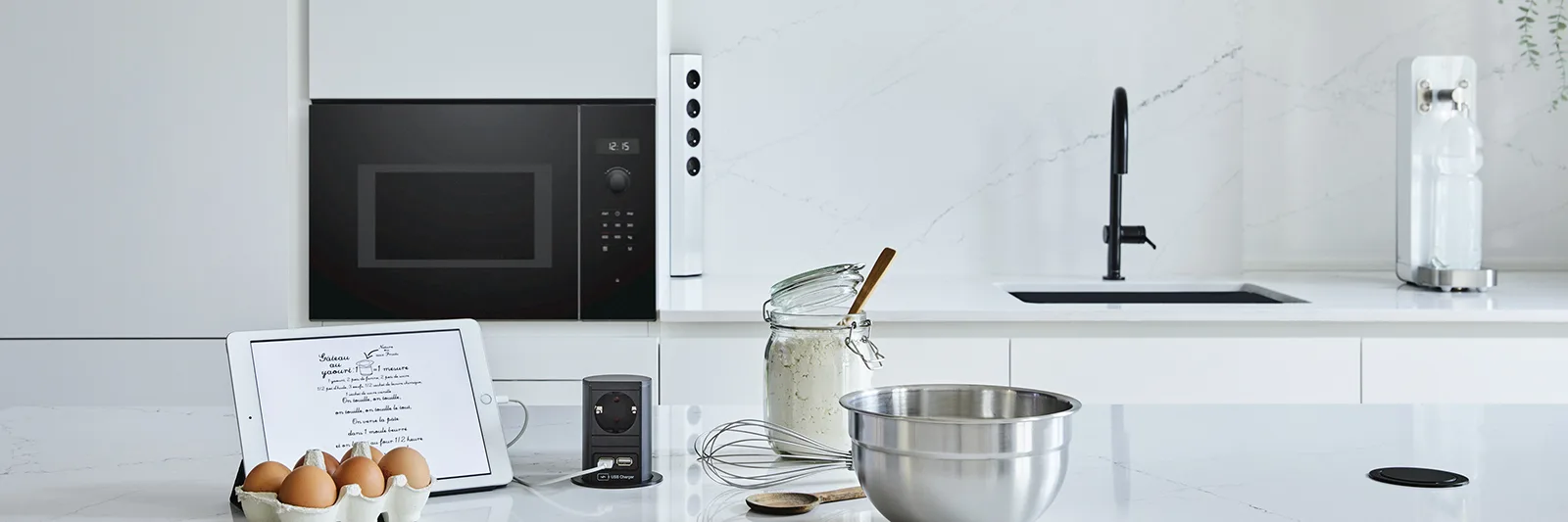 A white kitchen with a desk socket flush in the countertop