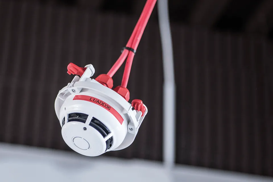 Smoke detector in the ceiling with a red Brother label and number