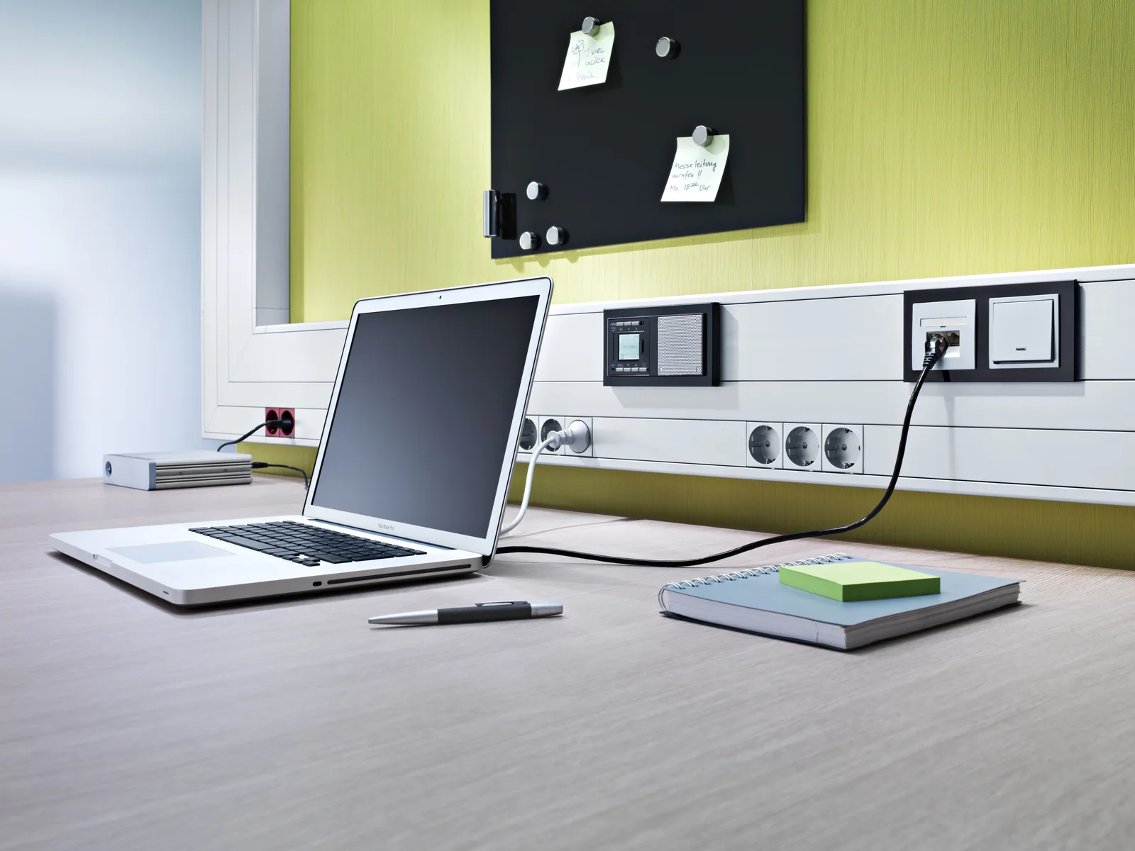 A socket channel on the wall with outlets above a desk with a laptop