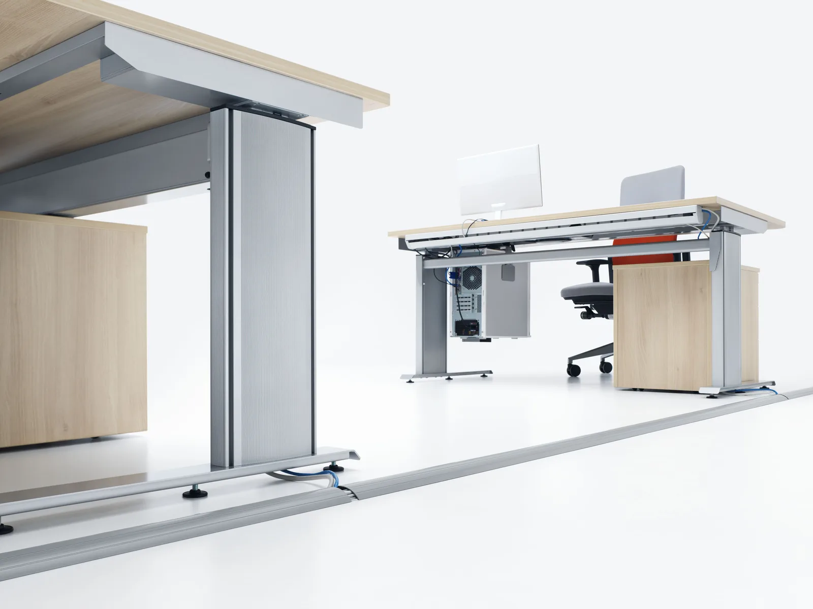 A gray floor channel over a cable to desks in a bright room