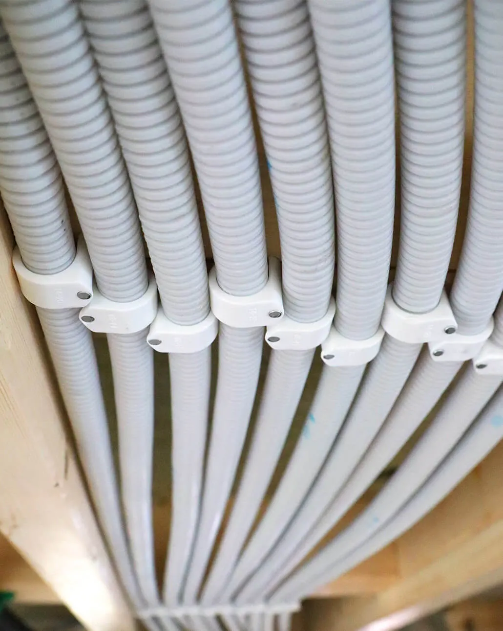 Conduits laid side by side in pipe clips under a timber ceiling