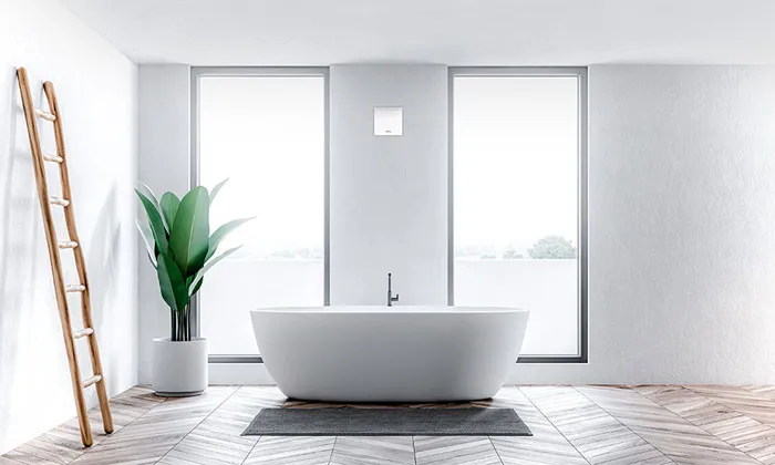 Bright bathroom with a freestanding bath and a Helios MiniVent fan on the wall
