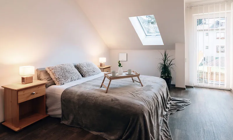 A bright attic bedroom with Helios ventilation on the wall