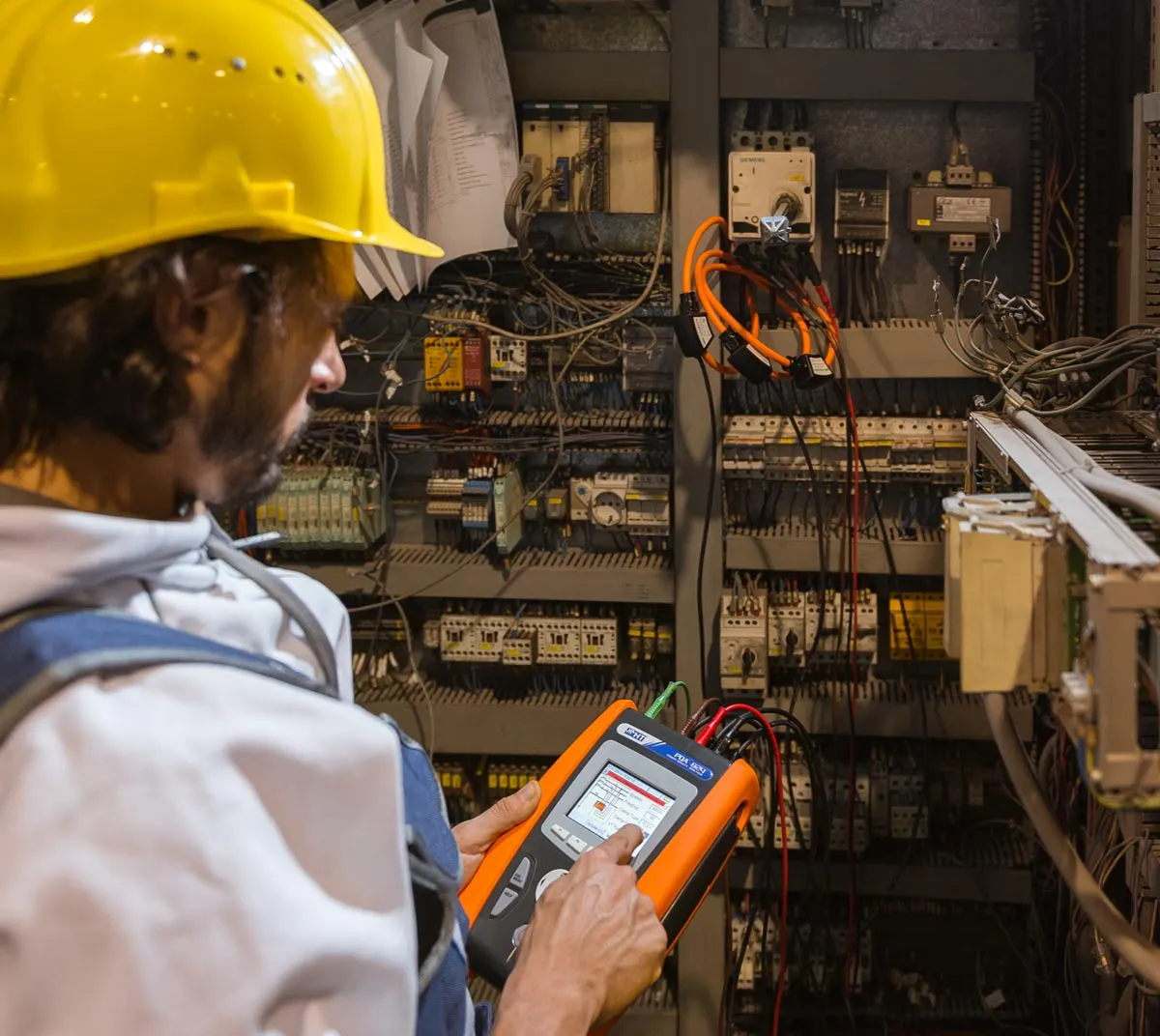 Electrician with an HT tester connected to a board