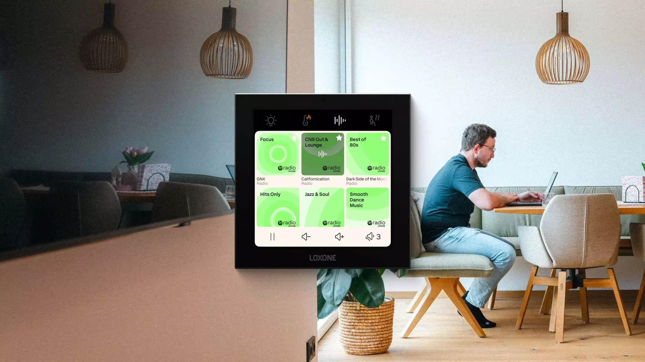 A Loxone Touch Pure Display on the wall in an open kitchen where a man works at the counter
