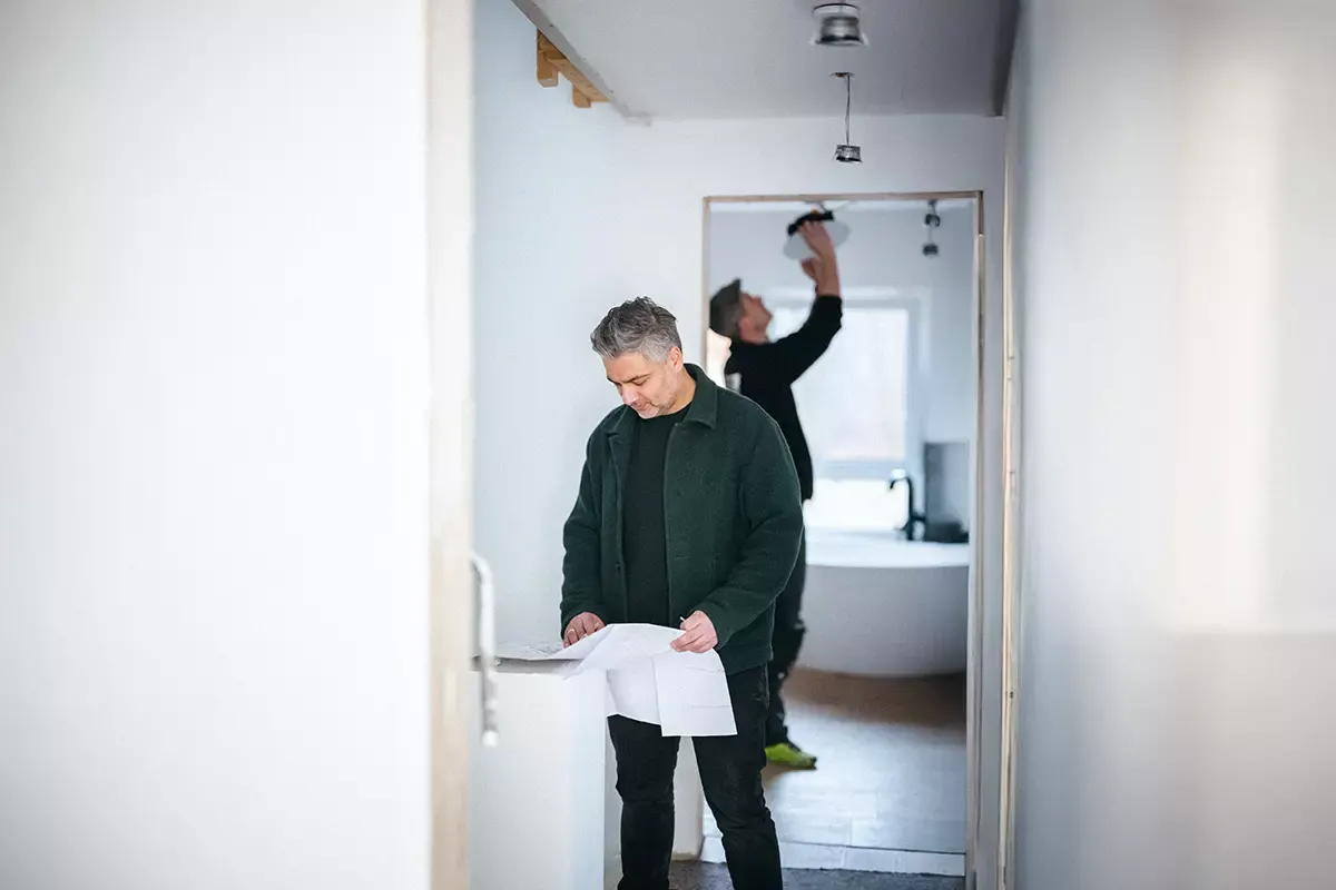 An electrician reviews a drawing in a house under wiring