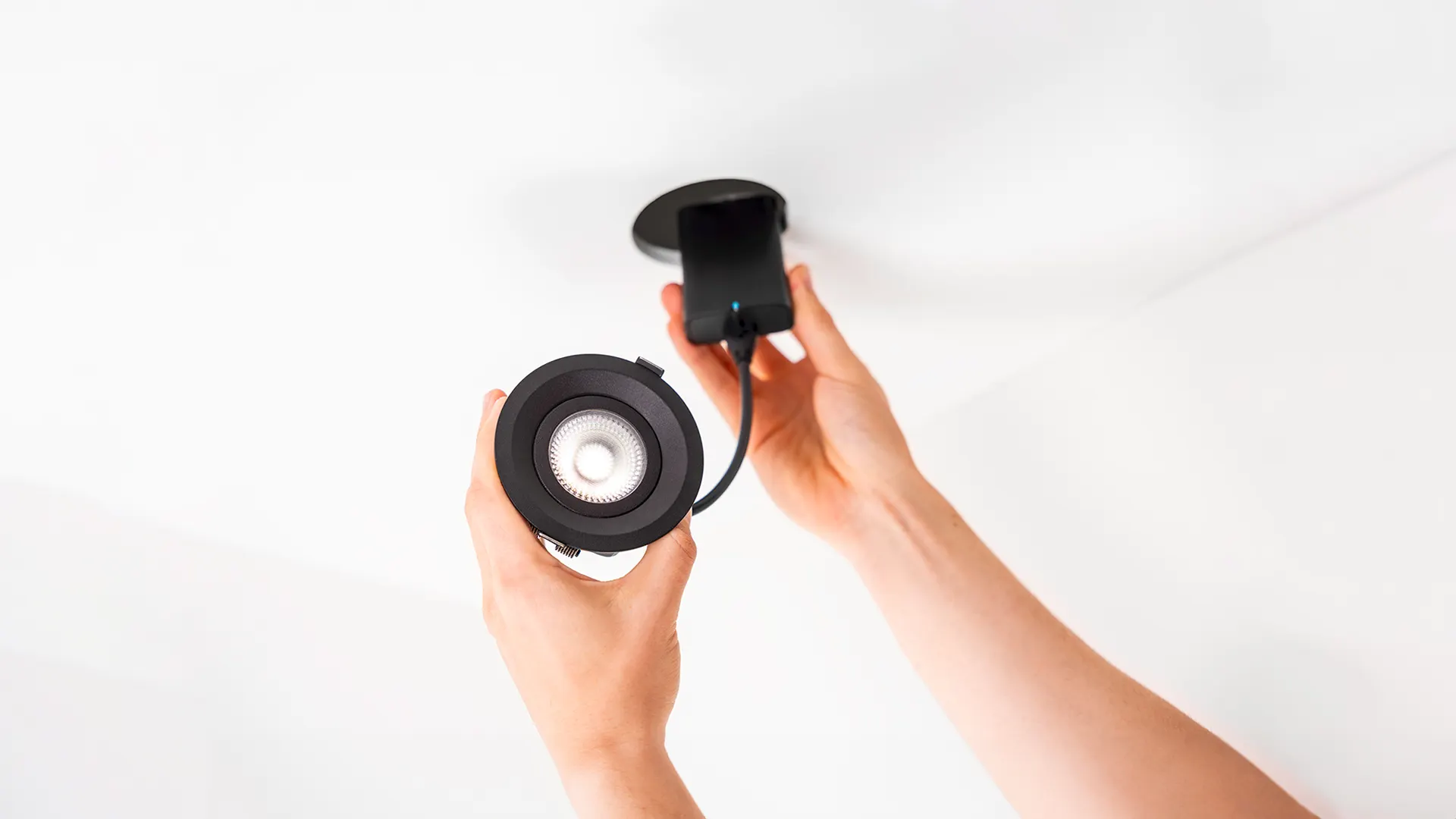 A recessed Plejd spotlight being fitted in a ceiling