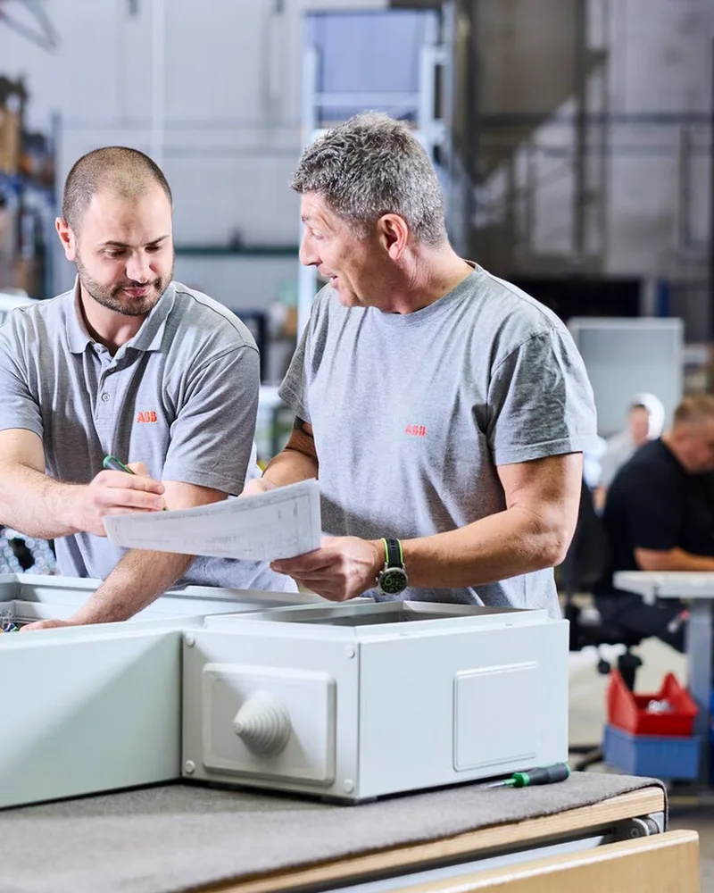 ABB Striebel & John staff go over a drawing at an open board cabinet