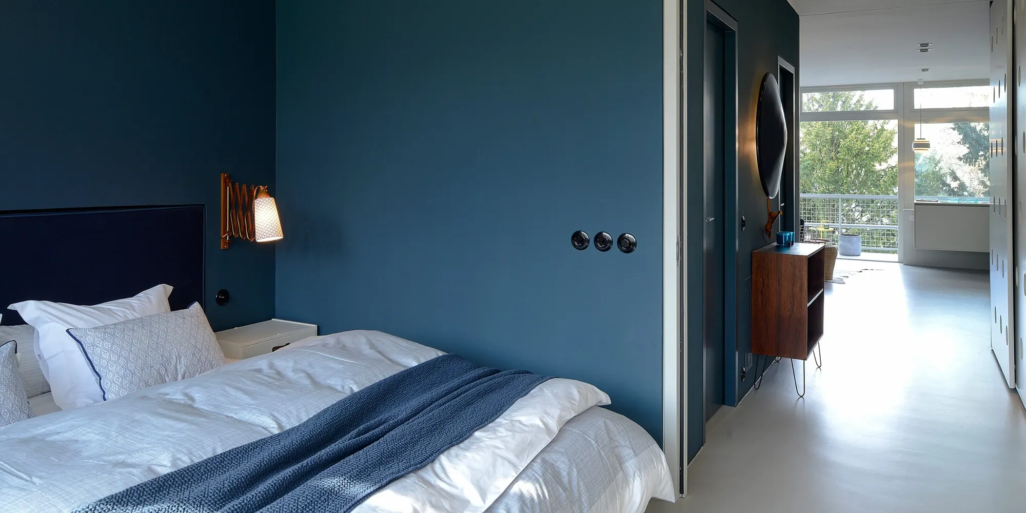 Bedroom with a dark blue wall and three black Bakelite switches