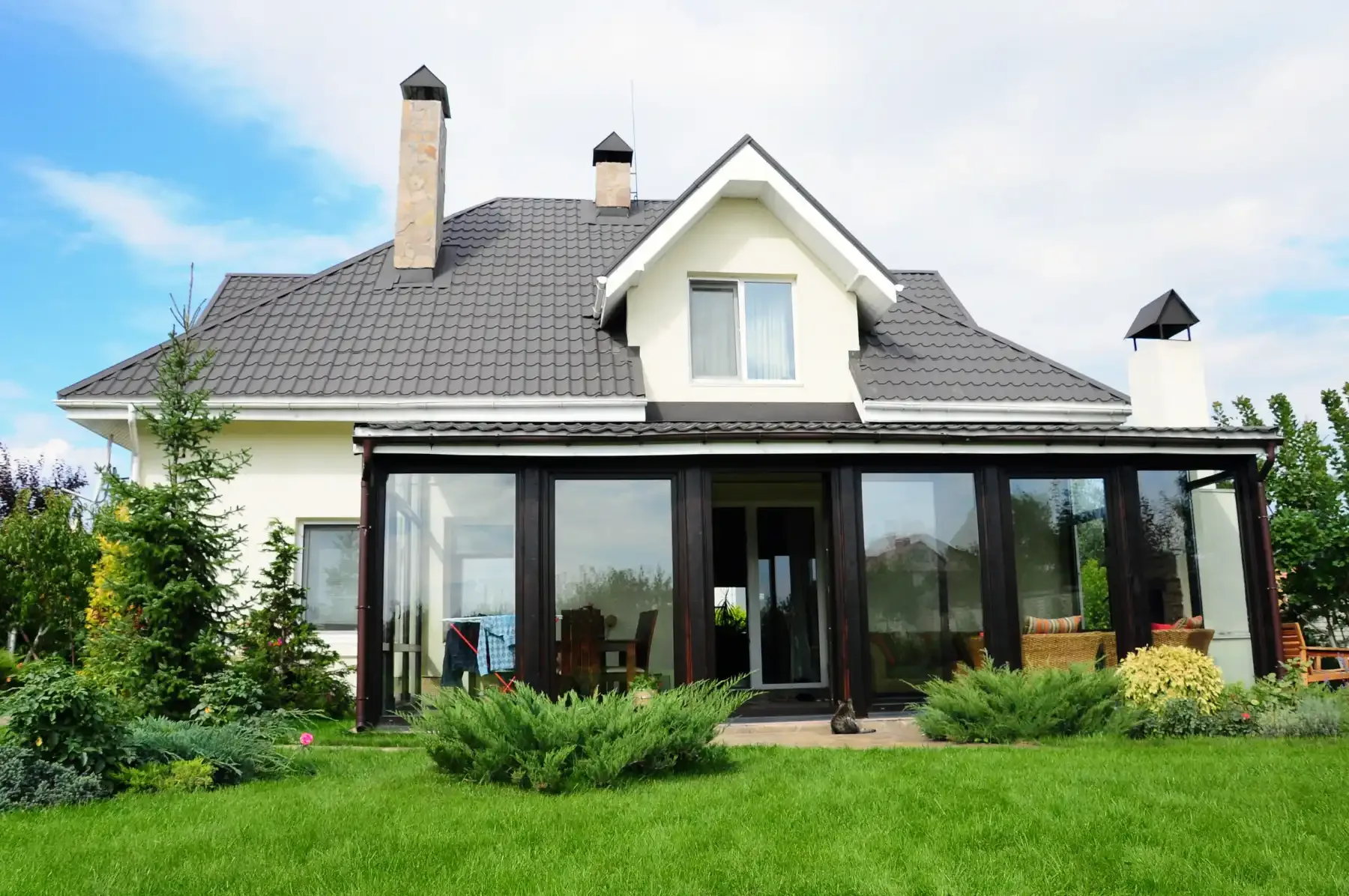A white detached house with a sunroom and a lawn