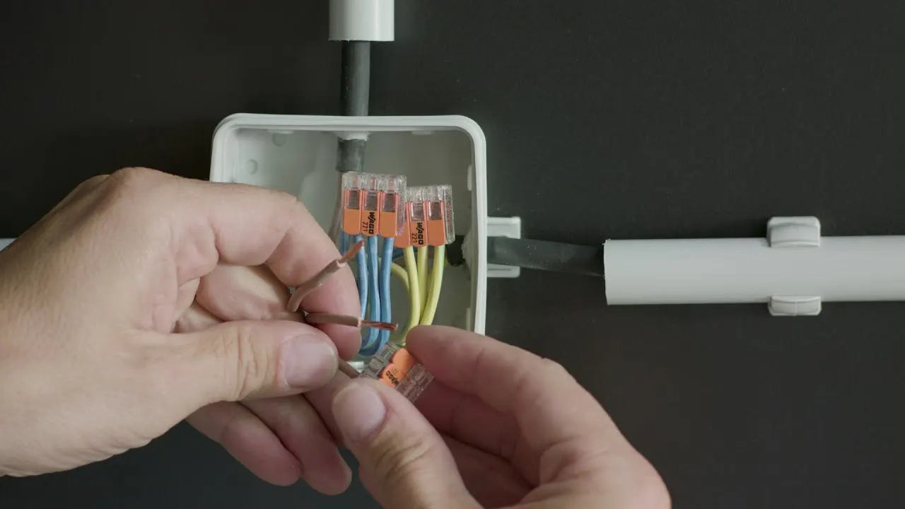 Hands connect a WAGO 221 in a junction box