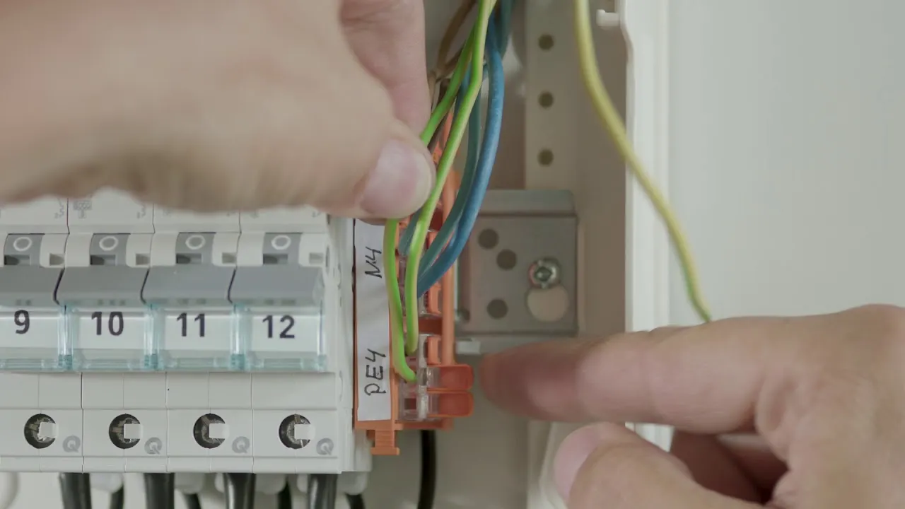 Hands connect a conductor with a WAGO 221 in a small panel