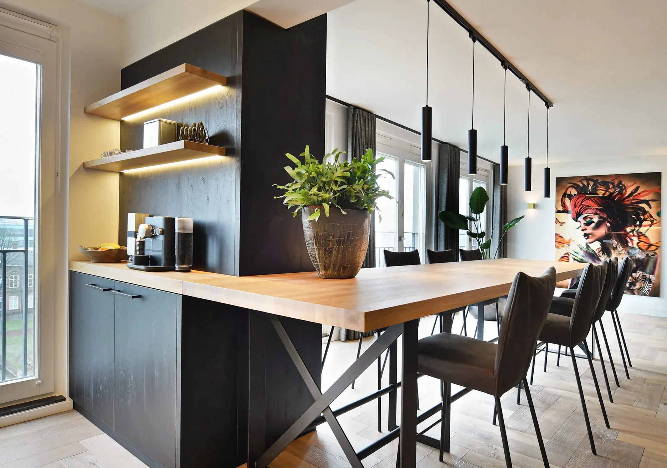 A dining room with a long wooden table and a row of black pendant lights on a track