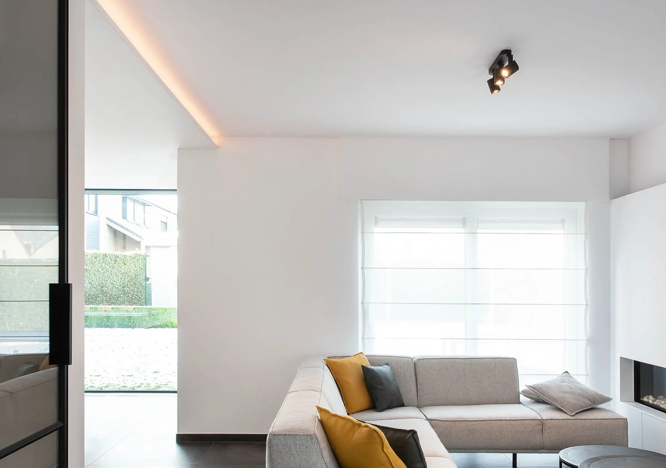 A bright living room with a corner sofa and a double spotlight in the ceiling
