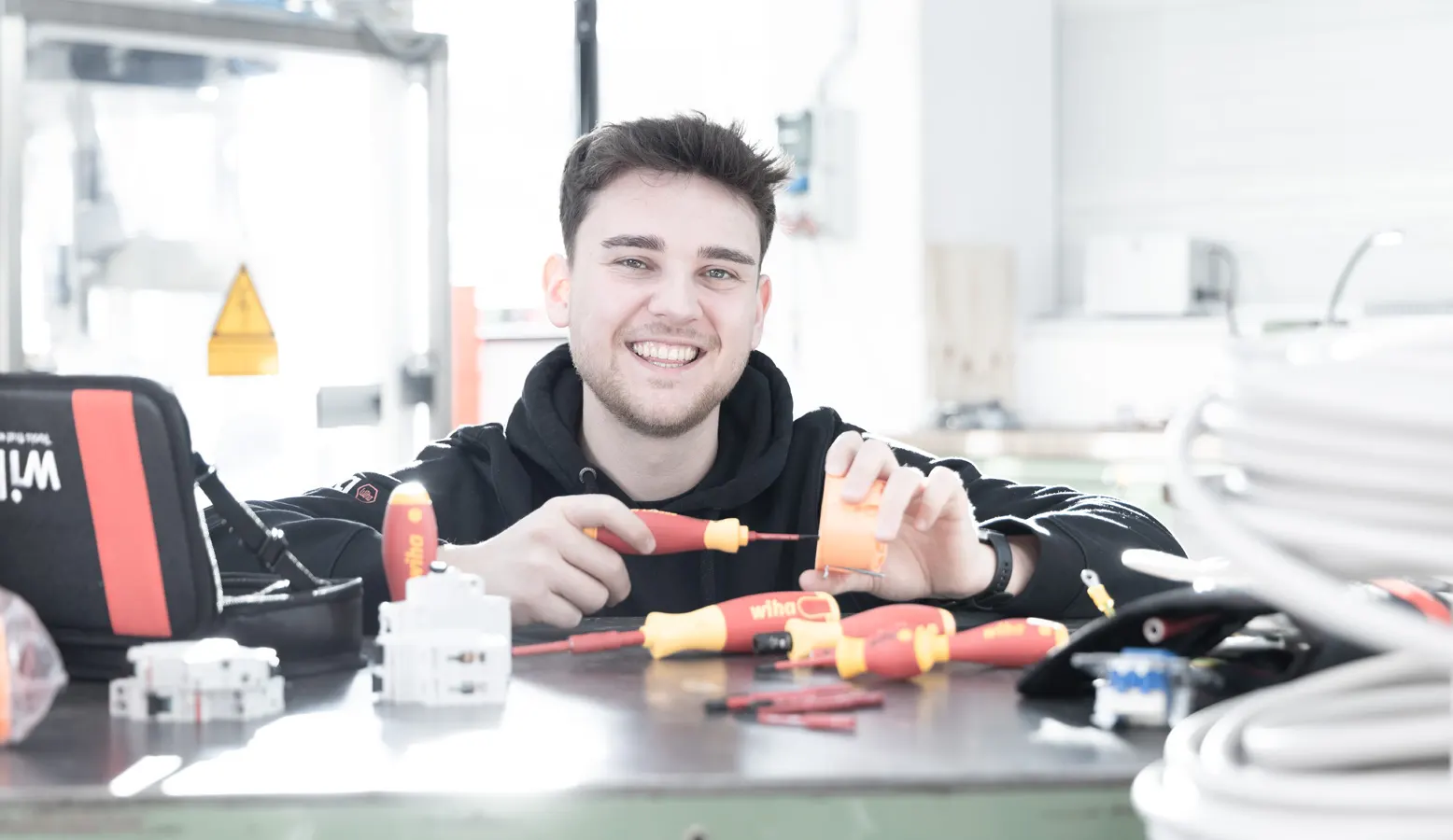 An electrician at a workbench with Wiha tools